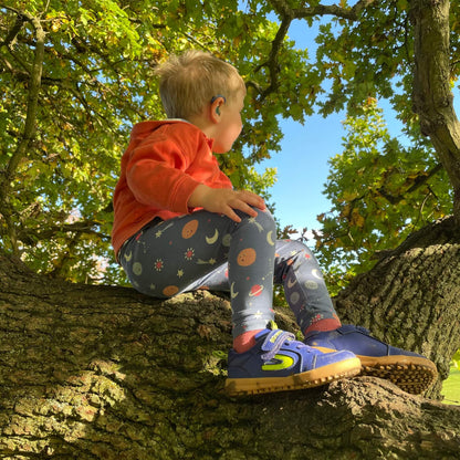 Boy wearing blue winter style trainers sitting in tree