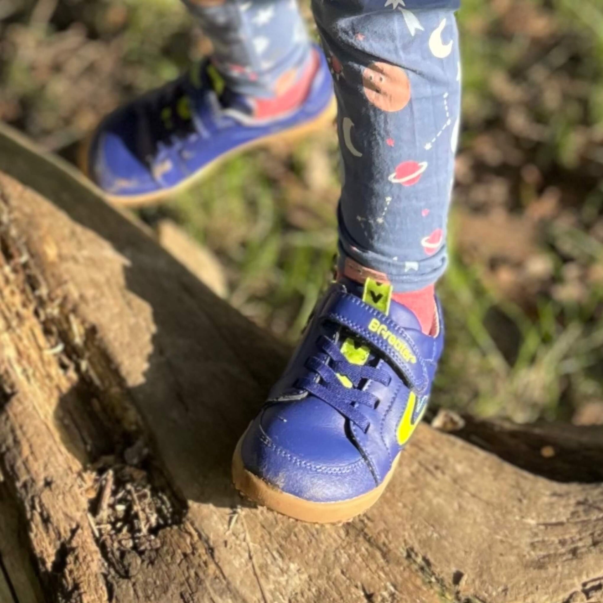 Close up of boy wearing blue trainers standing on log