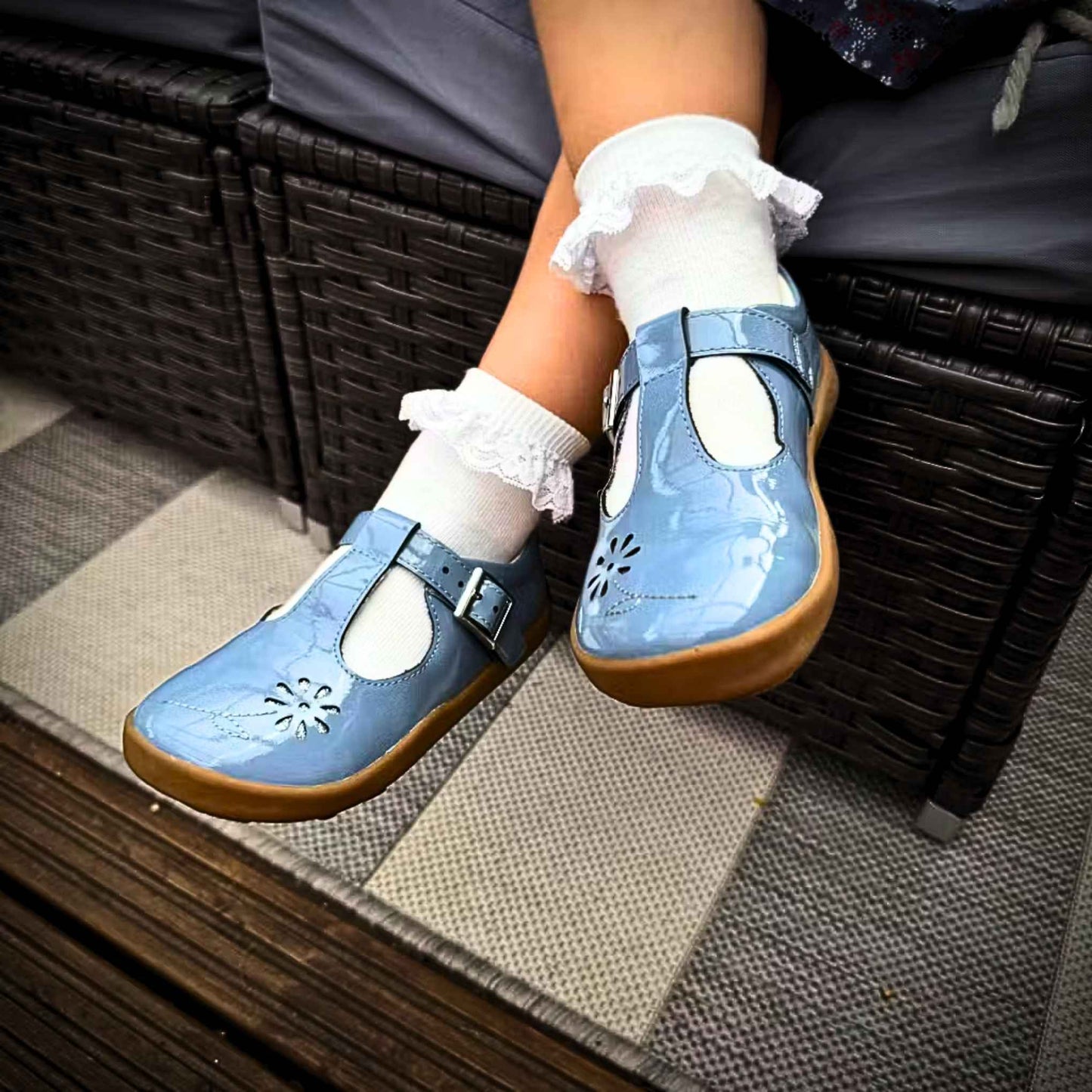 Girl siting down wearing blue girls shoes with flower detail